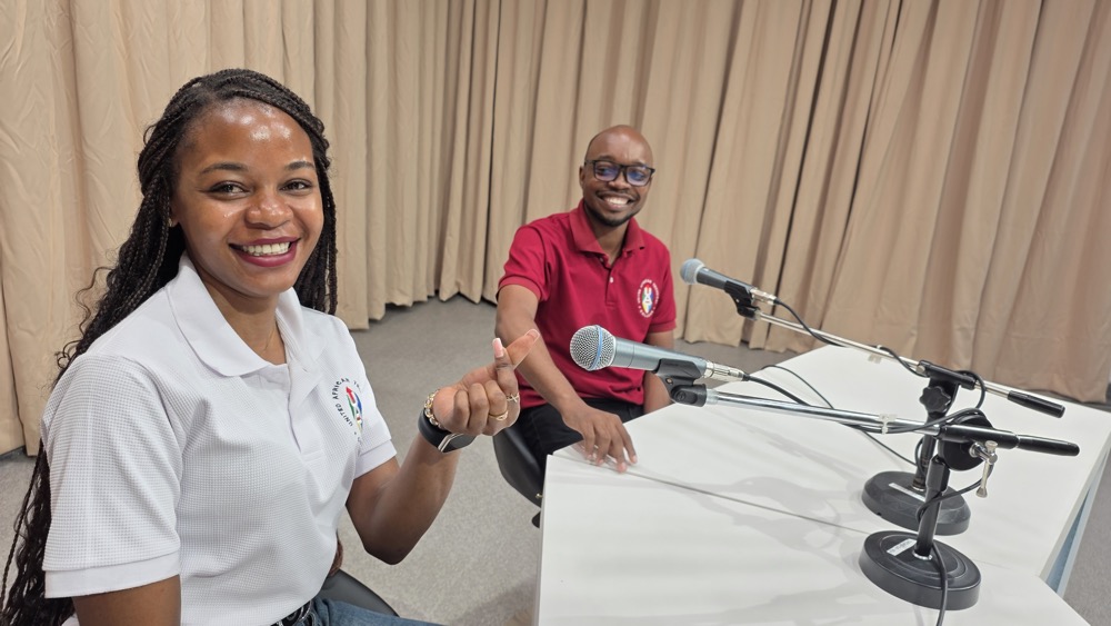 Two members of the UAUT community using microphones in a campus media studio